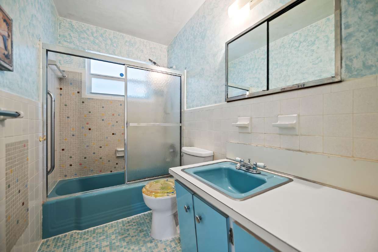 A dated bathroom with blue fixtures, mosaic tile, and worn finishes — before bjm interiors renovation specification